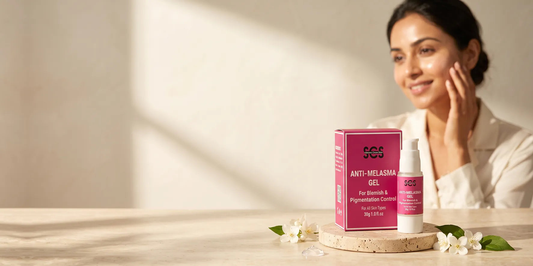 SCS Anti-Melasma Gel box and airless pump bottle on a travertine stone pedestal with a radiant South Asian woman
